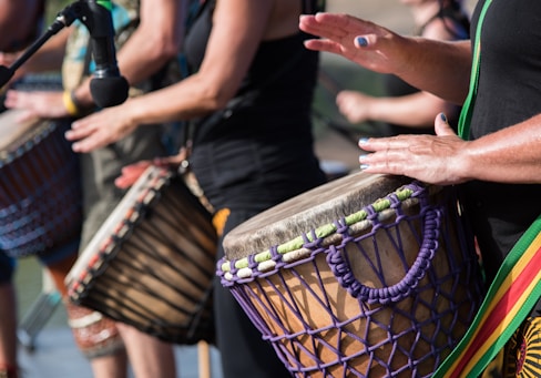 people playing goblet drums during daytime