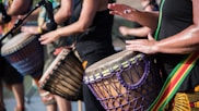 people playing goblet drums during daytime