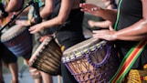people playing goblet drums during daytime