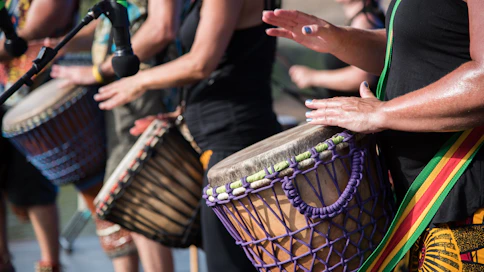 people playing goblet drums during daytime