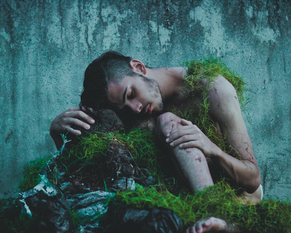 a man laying on the ground covered in moss