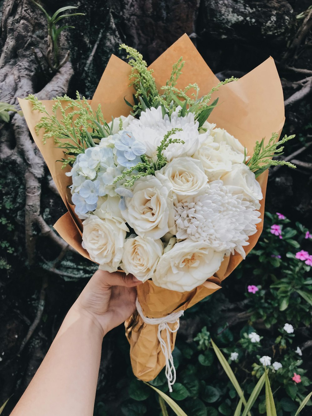 person holding beige and white flower bouquet