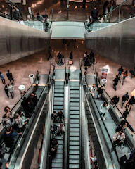 Technicians fitting a new escalator inside a busy urban shopping center.