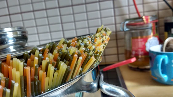 Close-up of a sleek black box with golden accents filled with steaming, colorful pasta.