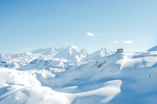 house on top of snow covered hills and mountains during day in Dolomites Italy