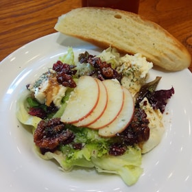 An inviting shot of a crisp kale and apple salad topped with walnuts and a drizzle of honey.