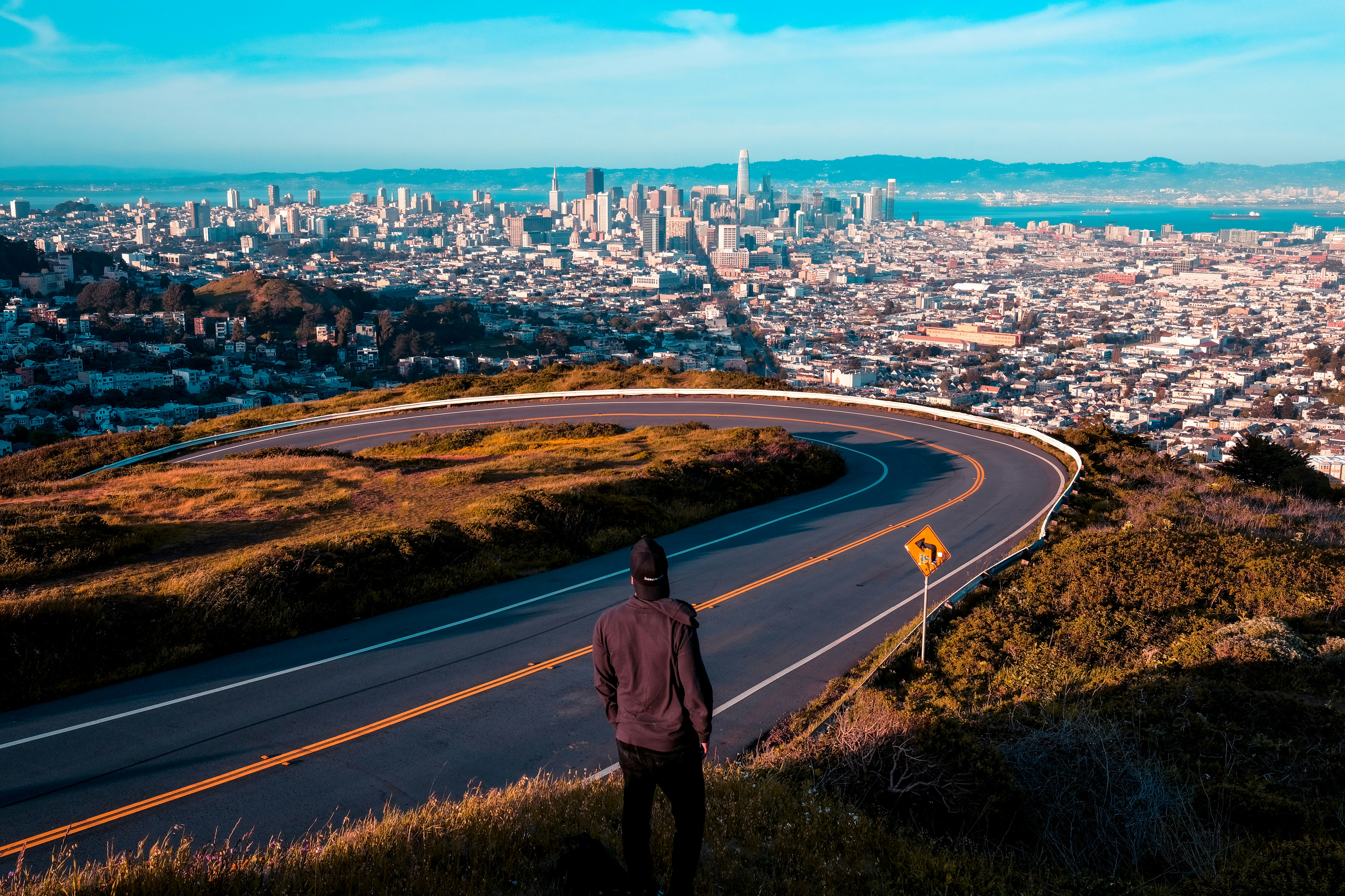 man standing near road looking at city buildings