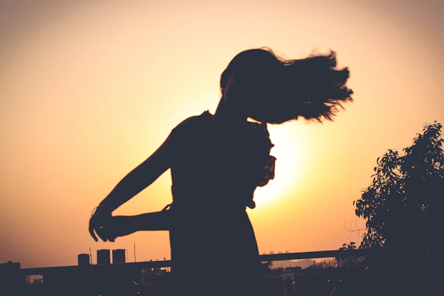 A silhouette of Jesus dancing gracefully under a golden sunset.