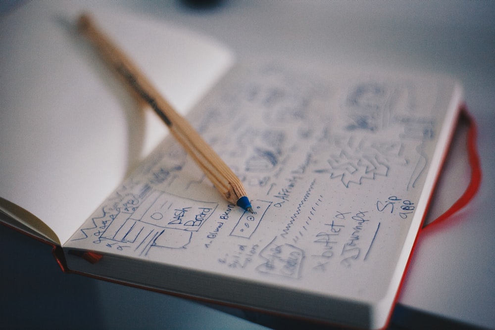 bolígrafo azul sobre cuaderno blanco