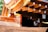 A detailed view of wooden architectural elements featuring smooth, curved surfaces and precisely cut beams. Copper or bronze metalwork adds a reflective quality to the structure, with sunlight enhancing the warm tones. The craftsmanship highlights traditional construction techniques.