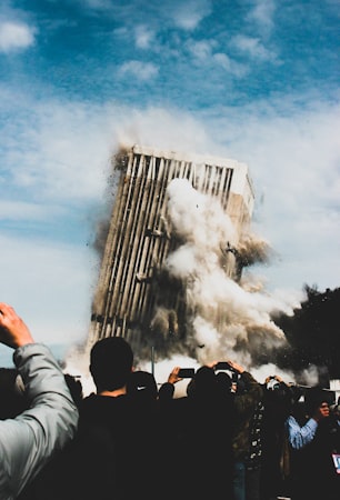 Onlookers photographing a partially collapsed building, the kind of scene that follows a roof failure at a commercial property
