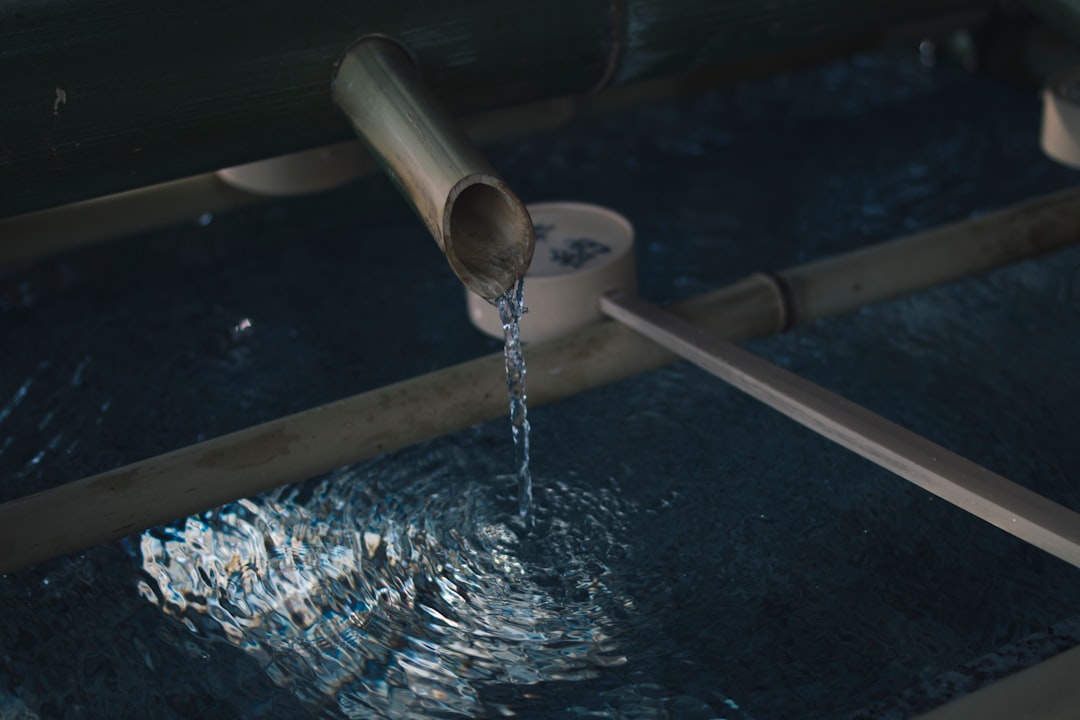 water flowing through brown wooden pipe into surface,