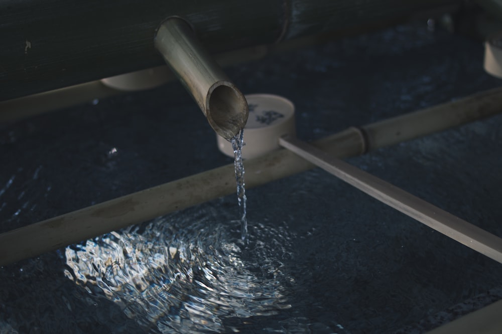 water flowing through brown wooden pipe into surface