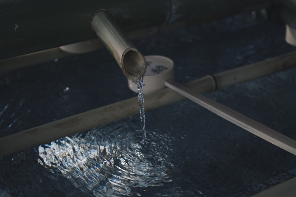 agua que fluye a través de una tubería de madera marrón hacia la superficie