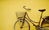 female beach cruiser bike leaning on yellow painted wall