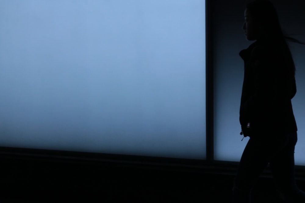 silhouette photo of woman looking at white surface