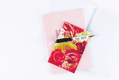 Soft blush pink notebook and gold pen on a nude beige desk.