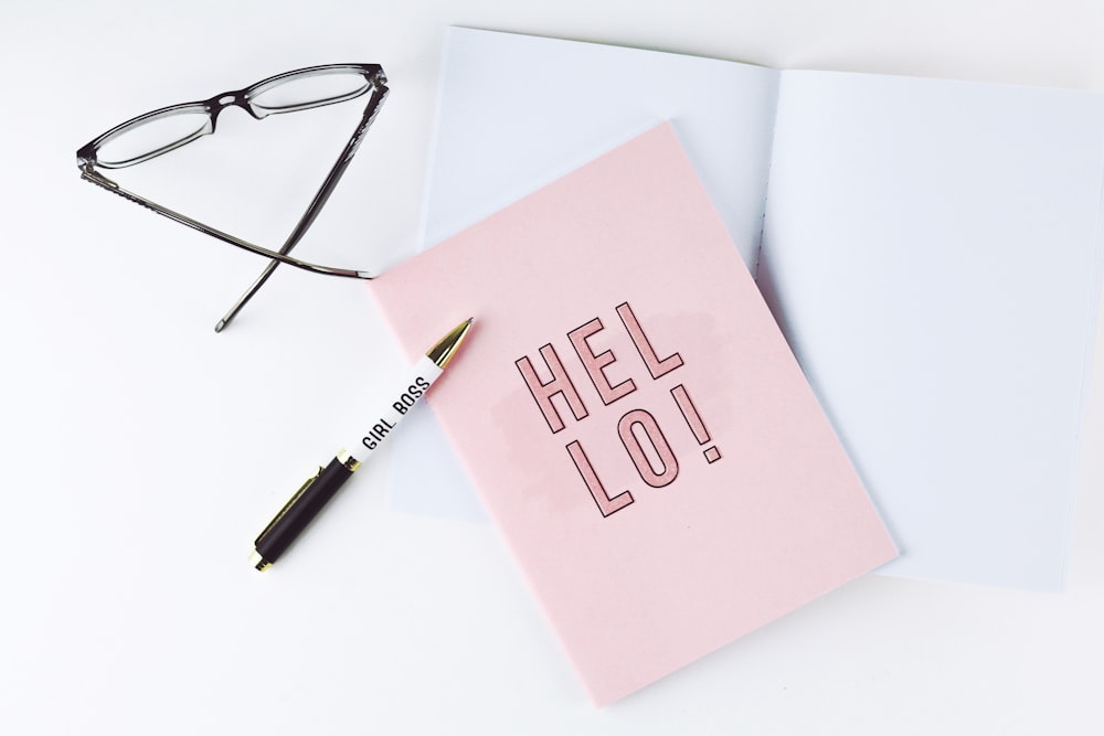 black ballpoint pen beside pink paper with hello written