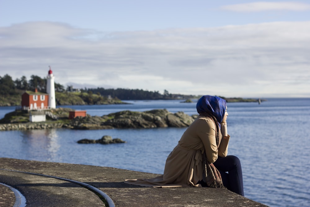woman sitting on dock near lighthouse