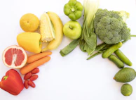 A colorful assortment of fresh fruits and vegetables arranged artistically on a white background.
