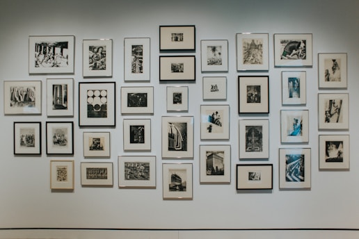 A monochrome photograph of an elegant gallery wall showcasing framed black and white artworks.