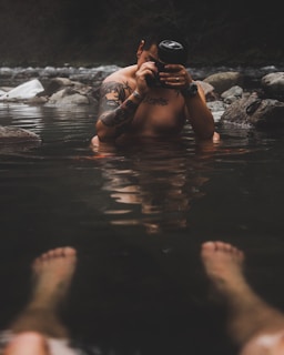 man holding camera while sitting on body of water