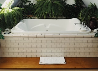 white bathtub surrounded with flowers