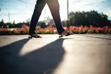 Person walking on a sunny path wearing blue and orange Sponch sandals, with lush greenery around.