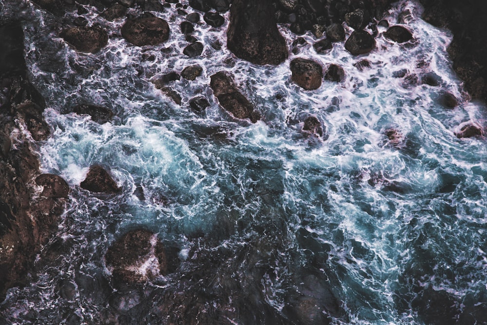 bird's eye view photography body of water crashing on rocks