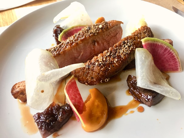A beautifully plated roast duck dish with vibrant vegetables.