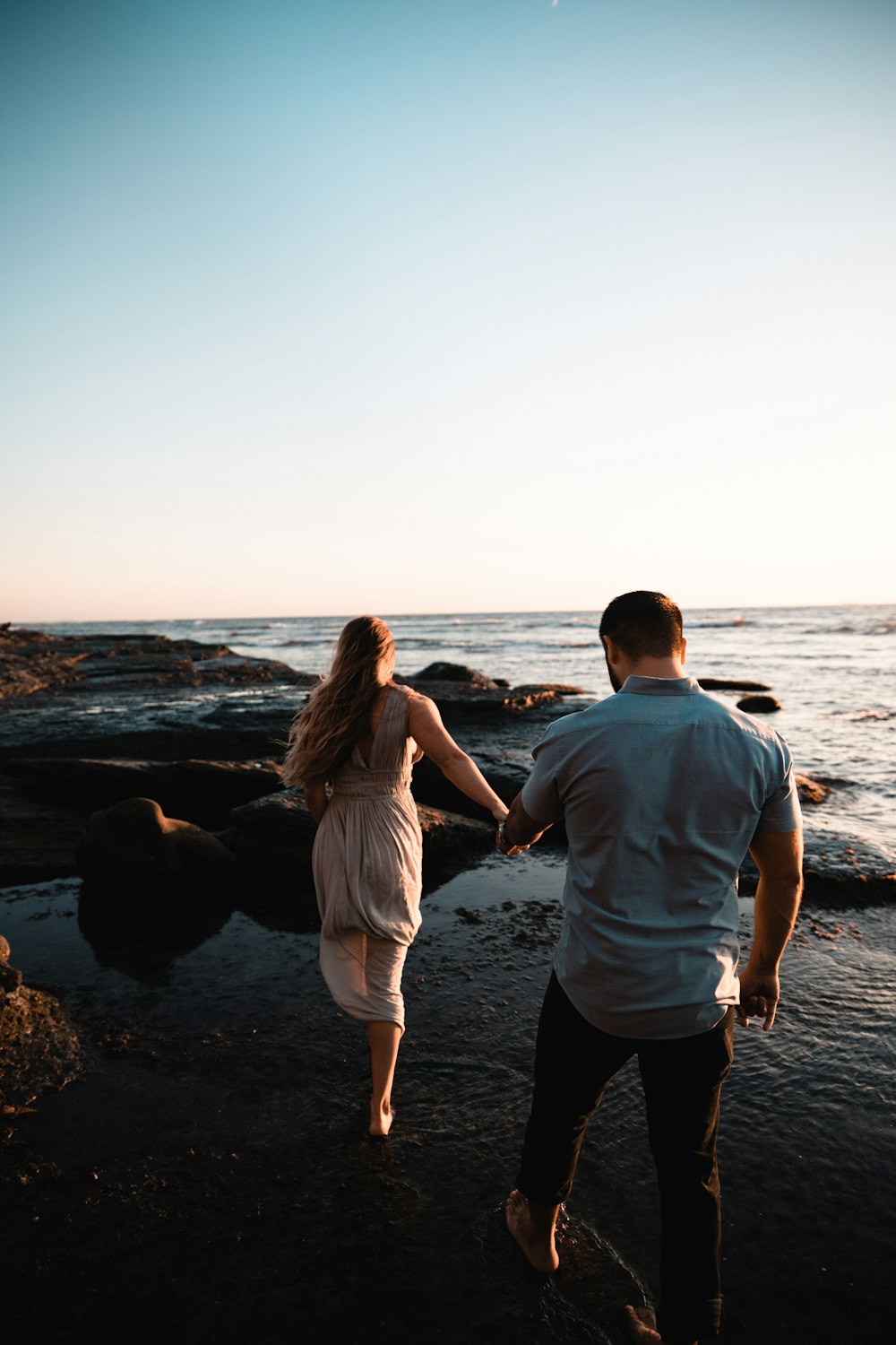 man and woman walking on seashore