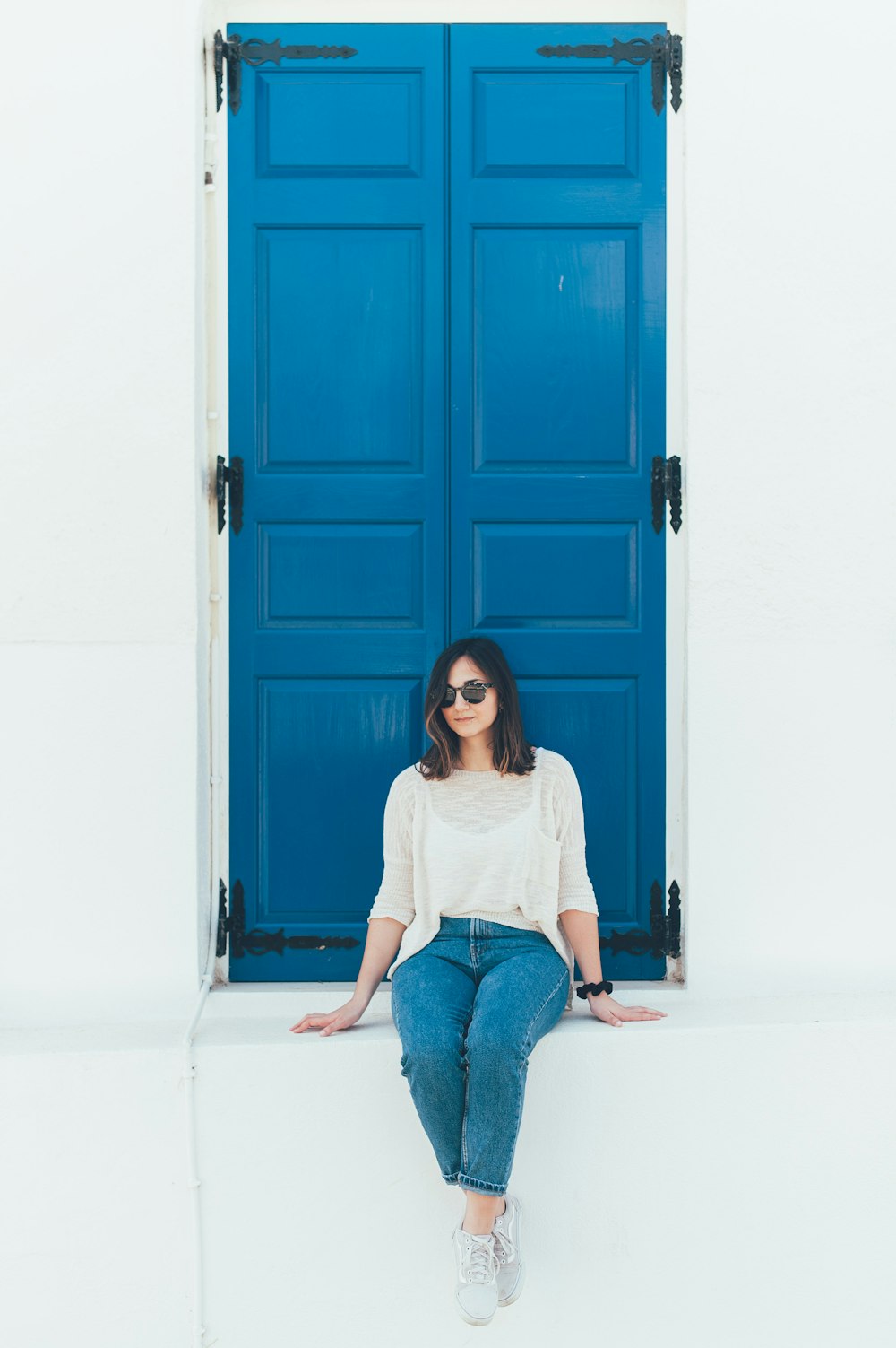 woman in white shirt sitting on concrete surface