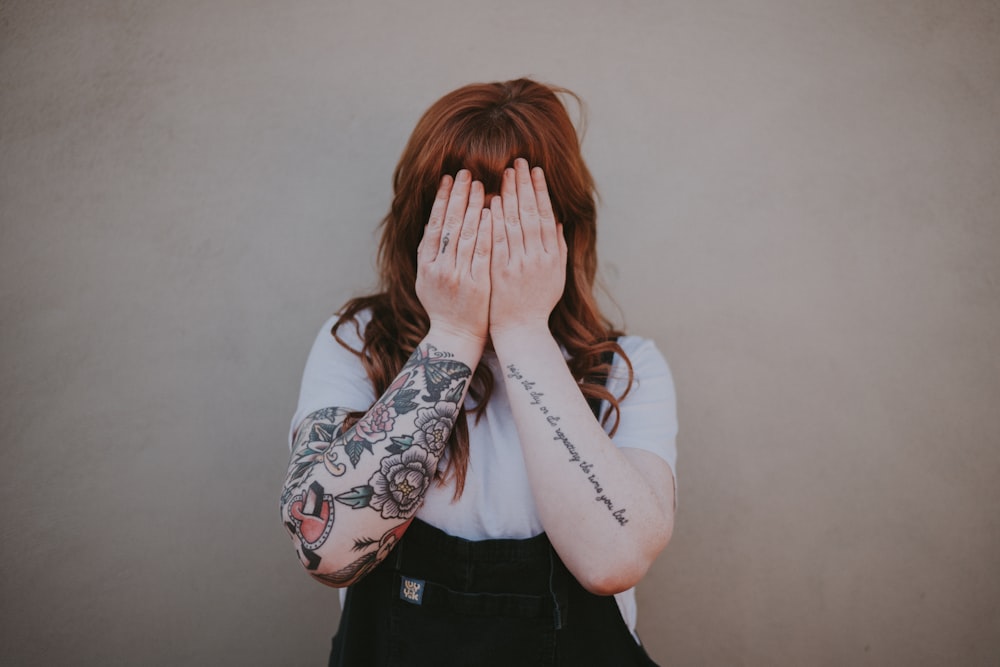 woman covering her face in front of wall