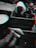 A hand holds a few folded pieces of paper with text on them. A wooden container holds a roll of paper towels and a cup with utensils. The image appears to have a glitch or distortion effect.