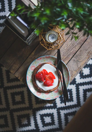 A vibrant strawberry shortcake topped with whipped cream and fresh berries on a rustic wooden table.