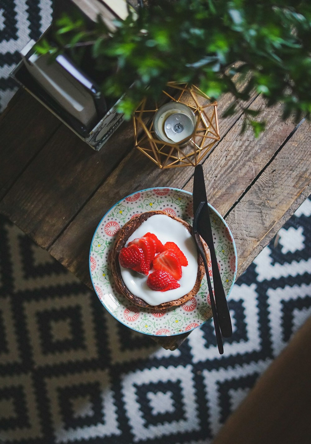 Tortita de chocolate con nata y fresa al lado del tenedor y el cuchillo