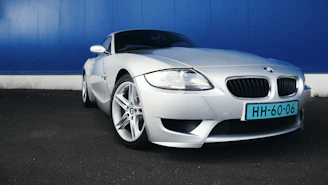 Side view of a sleek silver grand touring car with shiny rims against a dark wall