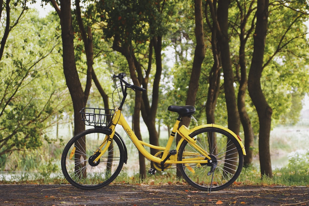photography of yellow bike parked near trees