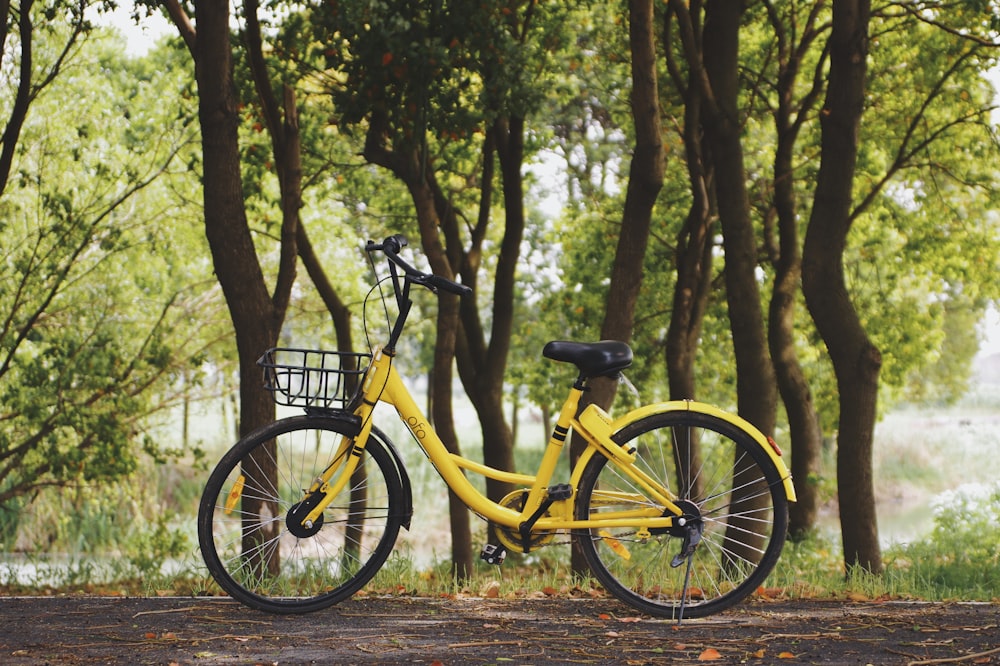 Photographie d’un vélo jaune garé près d’arbres