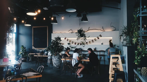 A sleek, dark-themed café interior with warm lighting and patrons enjoying coffee.