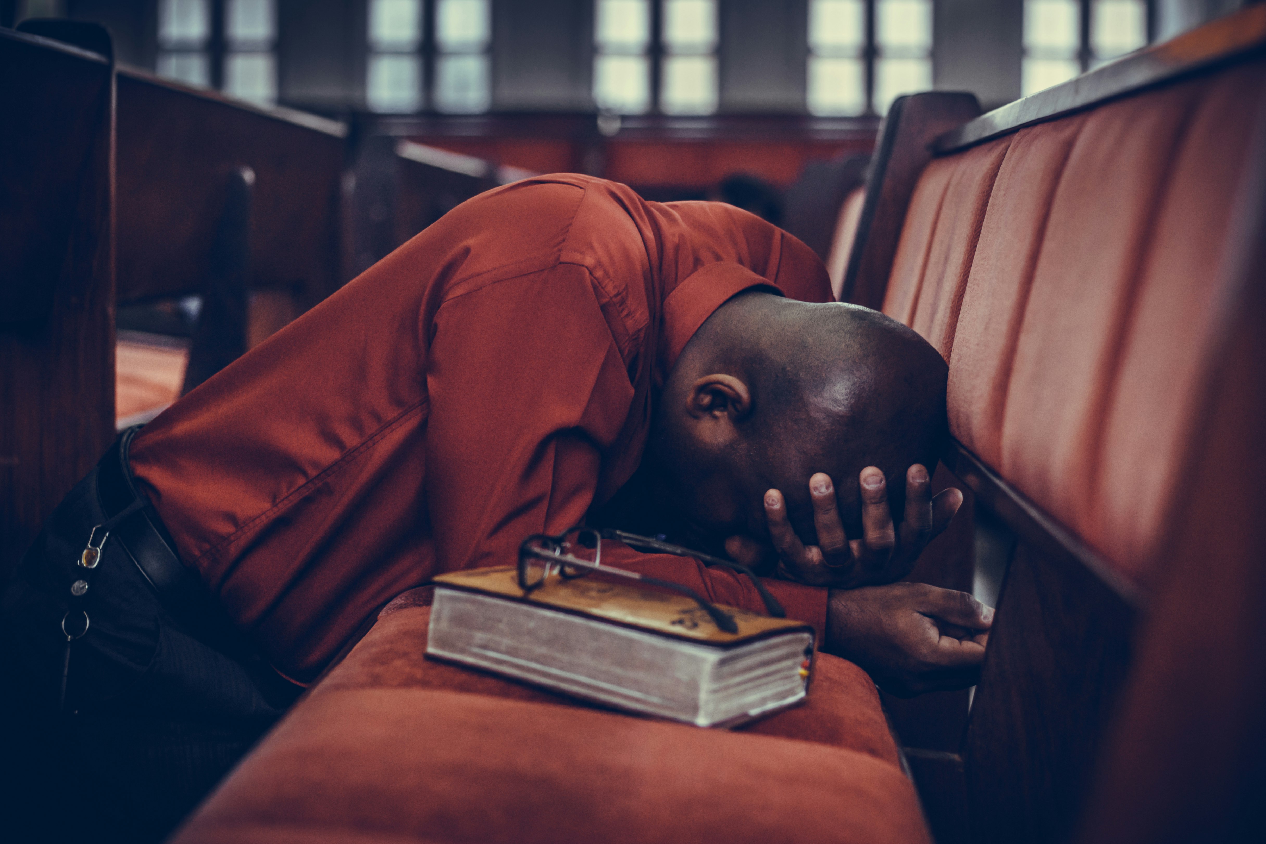 man in orange top beside eyeglasses on brown book