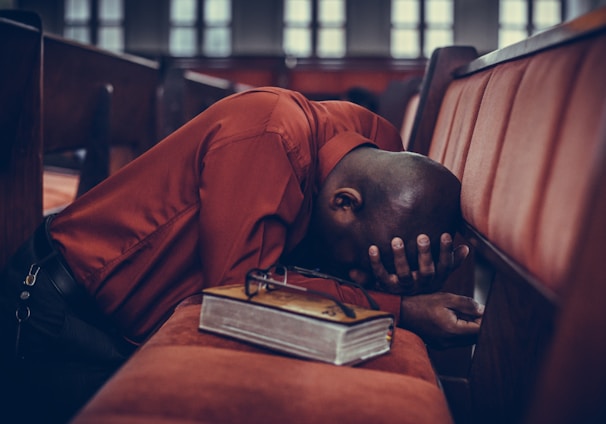 man in orange top beside eyeglasses on brown book