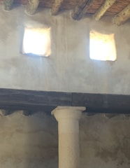 Rustic wooden beams and a stone wall with a small fireplace.