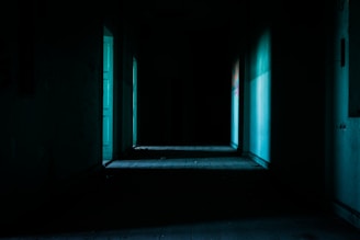 A shadowy, eerie hallway drenched in cold blue light hinting at unseen terror around every corner.