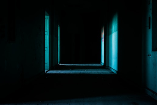 A shadowy, eerie hallway drenched in cold blue light hinting at unseen terror around every corner.