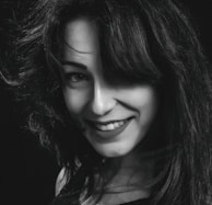 Soft black-and-white portrait of a client smiling confidently with her new hair replacement system.