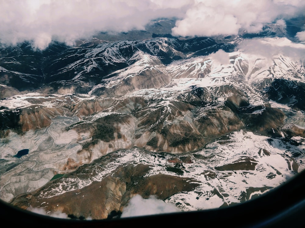 plane window showing snow filled moutain