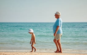 hombre mayor en la playa con su nieto, imagen ilustrativa