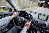 man driving Audi car on asphalt road