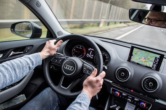 man driving Audi car on asphalt road